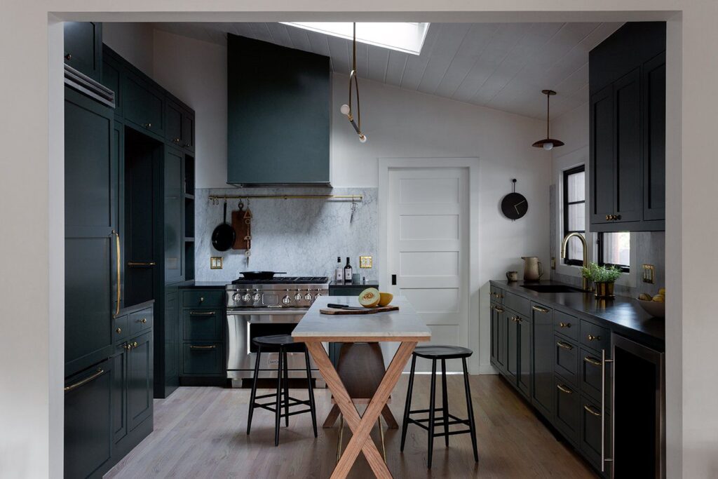 Modern kitchen with dark green cabinets, marble backsplash, wood island, and two black stools—an inspiring design often crafted by top kitchen remodeling companies.