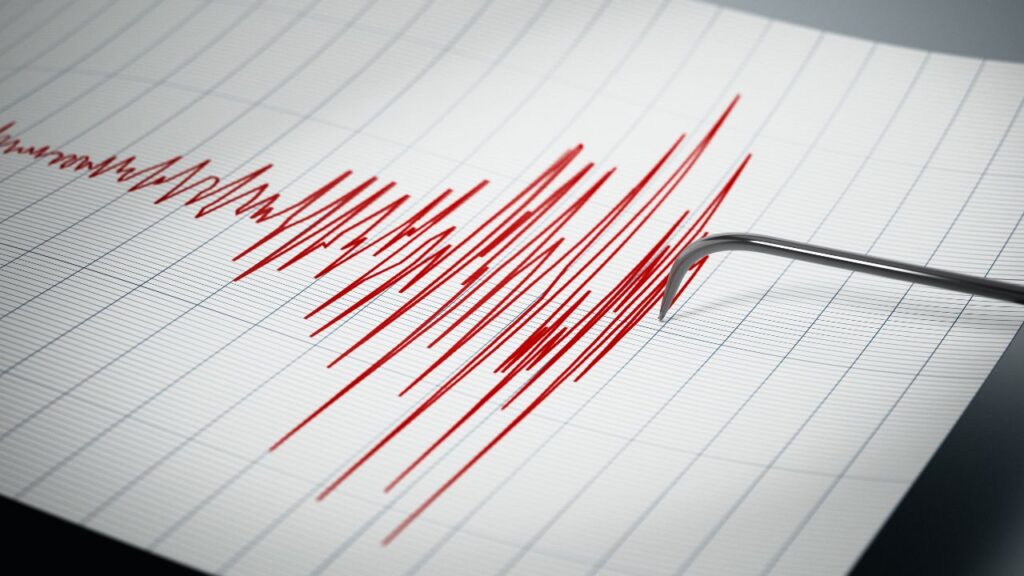 A seismograph drawing red, jagged lines on graph paper signals earthquake activity, providing vital data for general contractors assessing structural safety.